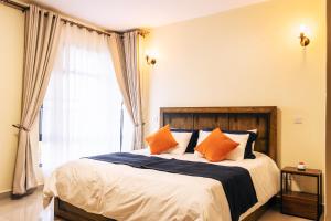 a bedroom with a bed with orange pillows and a window at Sophie's World- 2 Bedroom luxury apartment in Lubowa +19 photos