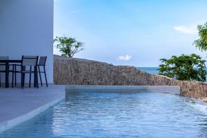 a swimming pool with a table and chairs next to a wall at Karafuu Beach Resort & Spa in Pingwe