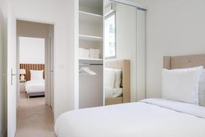 a white bedroom with a bed and a mirror at Spacious apartments for 6 people #3 in Asnières-sur-Seine
