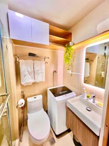 a small bathroom with a toilet and a sink at Scandi-Style & Organic condo Shore 3 MOA in Manila