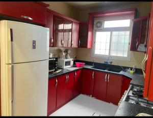 cocina con armarios rojos y nevera blanca en Alwaha-Appartement en Riad