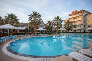 uma grande piscina com cadeiras e guarda-sóis num hotel em Godija Hotel & Suites em Velipoja