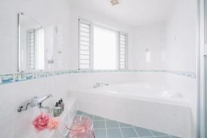 biała łazienka z wanną i umywalką w obiekcie 七色の海 Rainbow Sea w mieście Ukaji