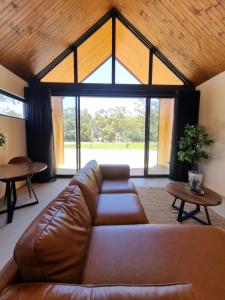 a living room with a leather couch and a large window at Chalet Hills in Sampsons Flat