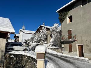 una calle cubierta de nieve con un edificio y un coche en LE MOULIN DE NAVETTE -La Roue en Aigueblanche