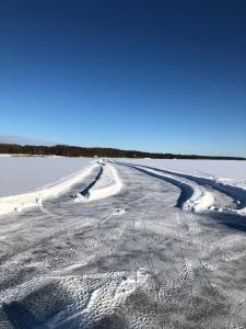 an empty road in the snow on a field at Tunnelmallinen kaksio hirsitalossa 