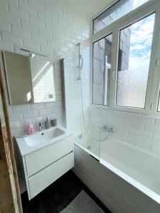 een witte badkamer met een wastafel en een bad bij Boho Apartments - 2 Bedrooms in Antwerpen
