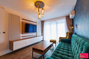 a living room with a green couch and a tv at The Cozy One in Târgu-Mureş