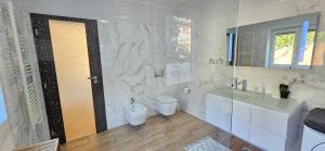 a white bathroom with a toilet and a sink at Istrian Lux Residence in Koper