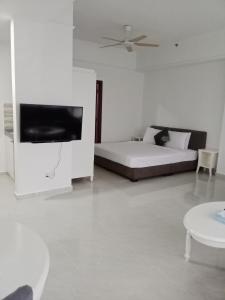 biały pokój z łóżkiem i telewizorem z płaskim ekranem w obiekcie BBS APARTMENT AT TIMES SQUARE KUALA LUMPUR MALAYSIA w Kuala Lumpur