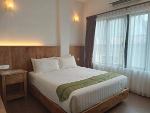 - une chambre avec un grand lit et une fenêtre dans l'établissement Swiss Hotel Heritage Boutique Melaka, à Malacca
