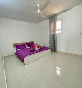Un dormitorio con una cama morada en una habitación blanca en AlRaha Chalet, en Badīyah