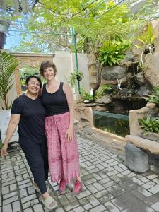 Dos mujeres posando para una foto frente a un jardín en Pujihouse One en Legian