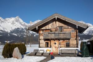 ein Blockhaus im Schnee mit Bergen im Hintergrund in der Unterkunft Chalet Steinerner Meerblick in Saalfelden am Steinernen Meer