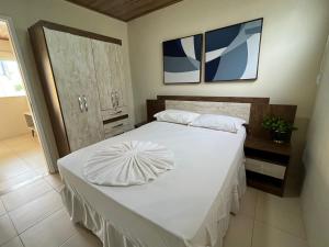 a bedroom with a large white bed with two pillows at Apartamento em Itaparica in Bôca do Rio