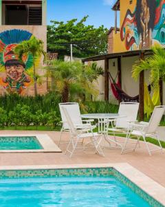 uma piscina com cadeiras, uma mesa e um mural em Apartamento em Itaparica em Bôca do Rio