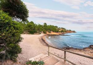 a sandy beach with a fence next to the ocean at Catalunya Casas Tranquil Paradise, Private Pool and only 200 meters to beach! in L'Ampolla