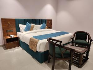 a bedroom with a bed and a chair at Emerald Suites in Greater Noida +27 photos