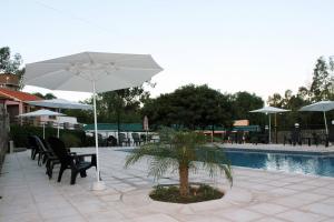 a table and chairs with an umbrella next to a pool at Complejo Turistico Alfombra Magika in Mendoza