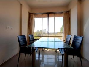 a dining room table with chairs and a large window at HAZYHILLS Staycation in Igatpuri