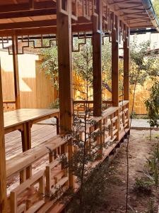 a wooden pergola with a wooden table and benches at Dungan House in Karakol