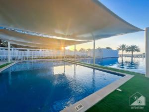 uma grande piscina num edifício com o pôr-do-sol em Luxurious 1B Seaview Apartment in JBR em Dubai