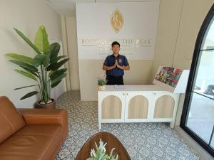 Un homme debout à côté d'une table dans une pièce dans l'établissement RoomQuest The Peak Patong Hill, à Patong Beach