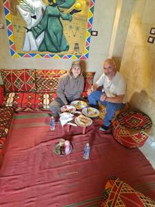 um homem e uma mulher sentados numa cama a comer comida em Queen House em Aswan