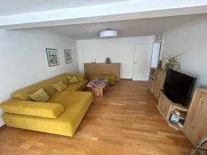 a living room with a yellow couch and a television at Wohnung direkt am Wald in Warstein