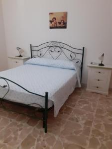 een slaapkamer met een wit bed met een metalen frame bij casa rosa in Tiggiano