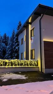 a white house with lights on the side of it at Apartmani Berg in Pale