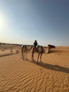 a woman riding on a camel in the desert at Infinity Camp in Bidiyah