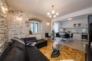 a living room with a leather couch and a stone wall at Stone House Kaštela in Kaštela