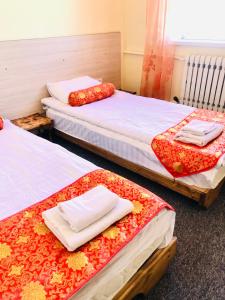 a room with three beds with towels on them at Dungan House in Karakol