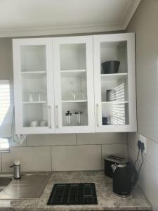 a kitchen with white cabinets with dishes in them at The Galton Villa in Windhoek