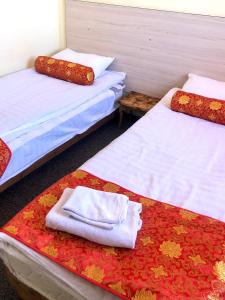 two beds with towels sitting on them in a room at Dungan House in Karakol
