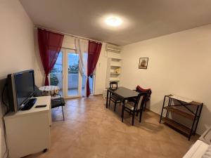 un soggiorno con TV e tavolo con sedie di Apartments "Helios" a Njivice