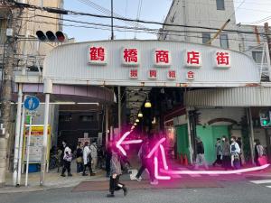 un grupo de personas caminando delante de una tienda en 難波心斎橋10 minutes民宿3号室 en Osaka