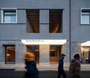 three people walking down a street in front of a building at Read and Rest Hotel in Beijing