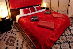 a bedroom with a large red bed with red sheets at Merzouga Highdune Camp With Heated Tents in Merzouga
