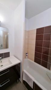 a bathroom with a sink and a tub and a mirror at Appartement AX - proche départ rando - piscine - balcon - Le blancflocon in Ax-les-Thermes