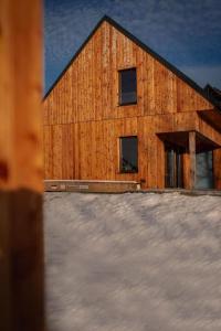 ein Holzgebäude mit Schnee davor in der Unterkunft Chaty Jagi in Czorsztyn