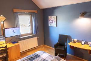 een slaapkamer met een bed, een bureau en een televisie bij Pension Kärnten in Seeboden