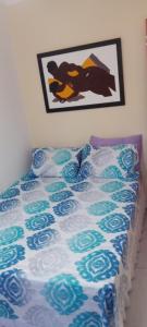 a bed with a blue and white comforter on it at Apartamento térreo, 2 quartos, 300m da praia de Atalaia, Aracaju in Aracaju