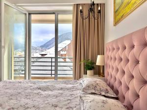 a bedroom with a pink bed and a large window at Central Premium Apartment in Braşov