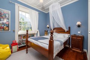 - une chambre avec des murs bleus, un lit et une fenêtre dans l'établissement Casa Grande da Camélia, à São Vicente