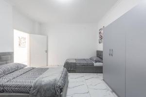 a white room with two beds and a refrigerator at Kilian Apartment in Shkodër