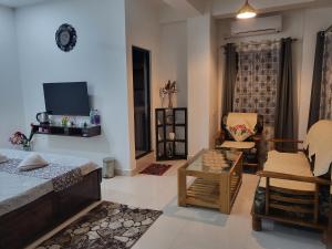 a living room with a bed and a chair and a tv at Hebron Haven in Jaigaon