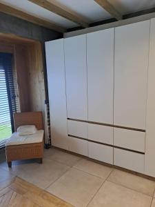 a bedroom with a large white wardrobe and a chair at Villa the Tulip JACK in Julianadorp