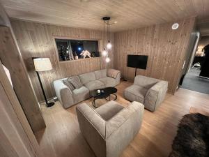 uma sala de estar com dois sofás e uma televisão em Moderne hytte på Fjellsætra, Ski in/Out, Familievennlig em Sykkylven